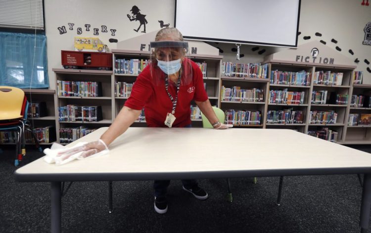 Garland Independent School District custodian Camelia Tobon wipes down a table in the library at Stephens Elementary School in Rowlett, Texas, on Wednesday.
