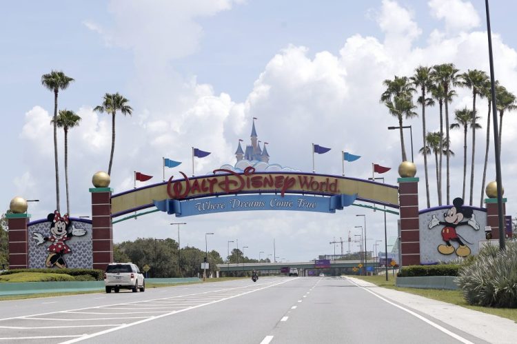Cars drive under a sign greeting visitors near the entrance to Walt Disney World. 