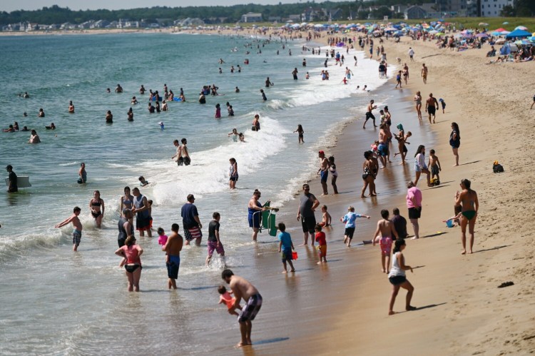 Crowds of people cool off on a hot August day on the beach in Old Orchard Beach.