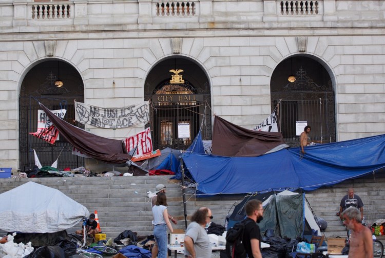 Protesters and volunteers begin taking down tarps and tents at City Hall Plaza on Aug. 7. 