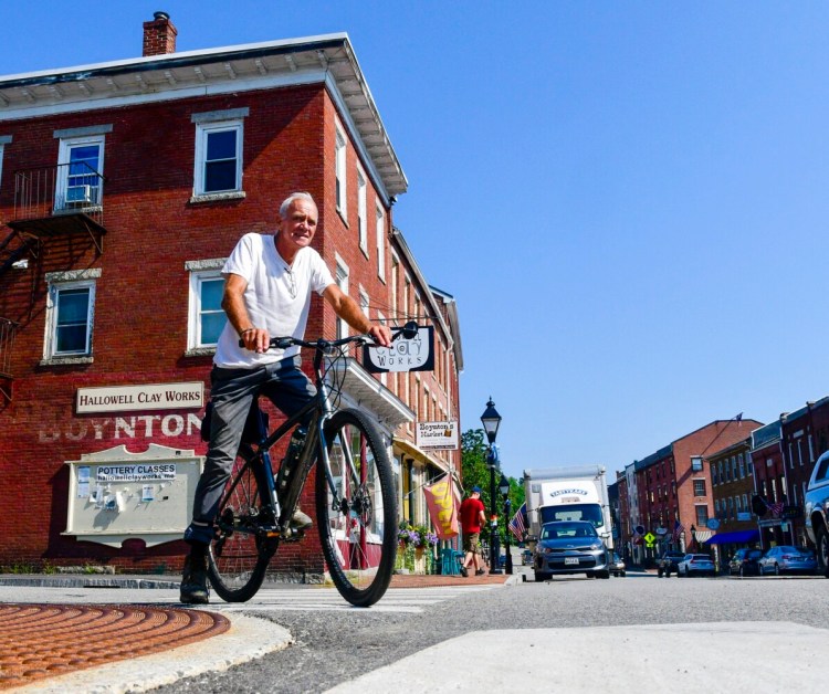 After a coffee break at Slate's Bakery, Austin Moore heads south Tuesday on the Kennebec River Rail Trail in Hallowell. 