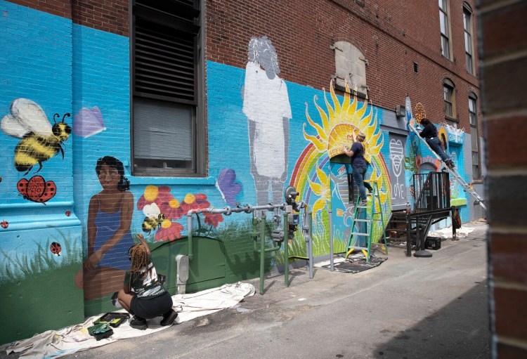 Candice Gosta, left, Karrin Parkinson and Sidney Sanchez, right, work on mural on the backside of 50 Monument Square in Portland on Sunday. (Derek Davis/Staff Photographer)