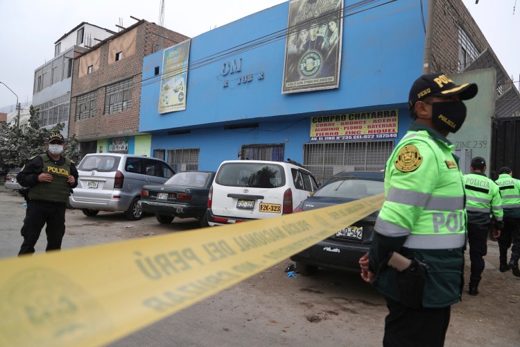 Police officers guard the perimeter of the Tomas Restobar disco in Lima, Peru, where officials say 13 people died on Sunday in a stampede after a police raid to enforce the country's lockdown restrictions. 