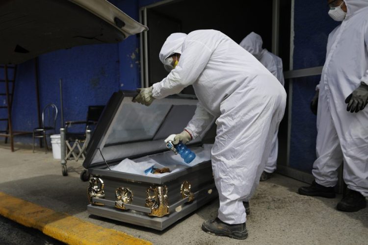 A worker sprays disinfectant solution inside the coffin of a person who died from suspected COVID-19, as the body arrives at the crematorium at Xilotepec Cemetery in Xochimilco, Mexico City, on Monday.
