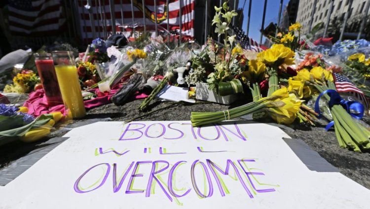 Flowers and signs adorn a barrier in 2013, two days after two explosions killed three and injured hundreds, at Boylston Street near the of finish line of the Boston Marathon at a makeshift memorial for victims and survivors of the bombing. 

