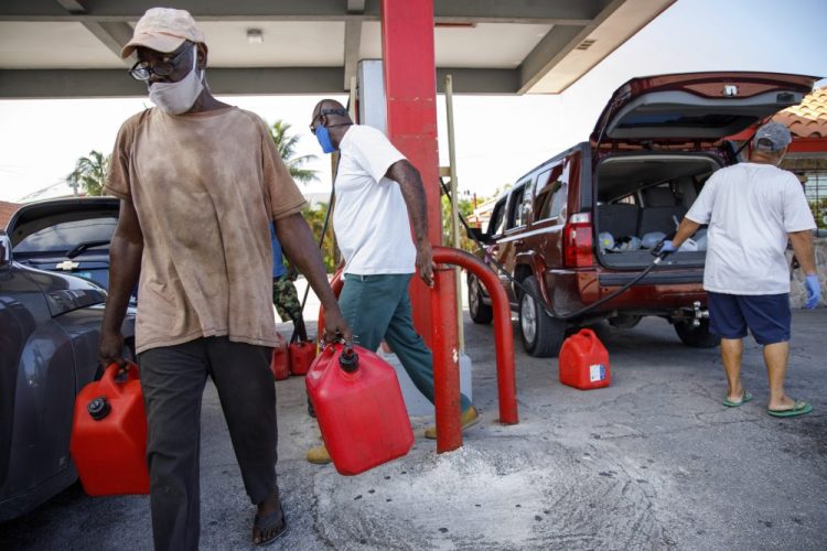 A resident walks with containers filled with gasoline at Cooper's gas station before the arrival of Hurricane Isaias in Freeport, Grand Bahama. 