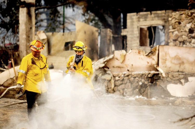 A Los Angeles County firefighter extinguishes hot spots at a scorched residence while battling the Lake Fire in the Angeles National Forest, Calif., north of Santa Clarita on Thursday.