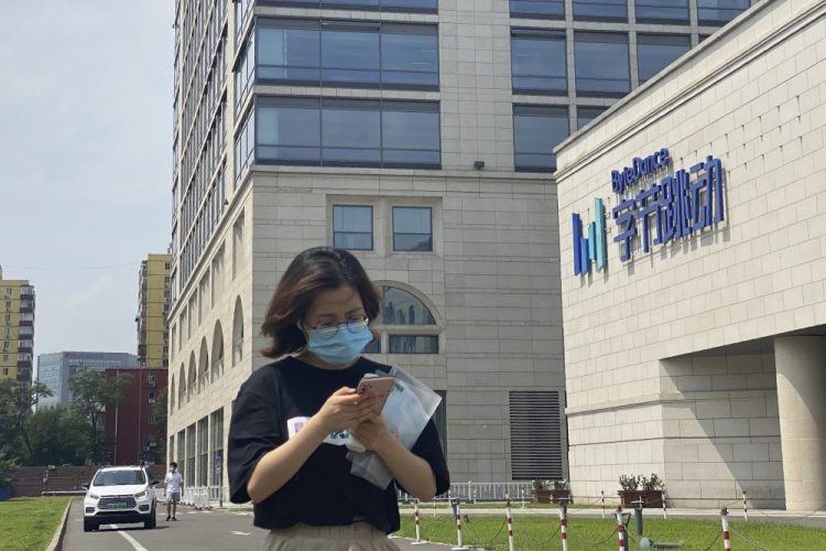 A woman passes by the ByteDance headquarters in Beijing. The Chinese government is complicating the U.S.-government-ordered sale of U.S. TikTok assets. 
China on Friday introduced export restrictions on artificial intelligence technology, seemingly including the type that TikTok uses to choose which videos to spool up to its users. 