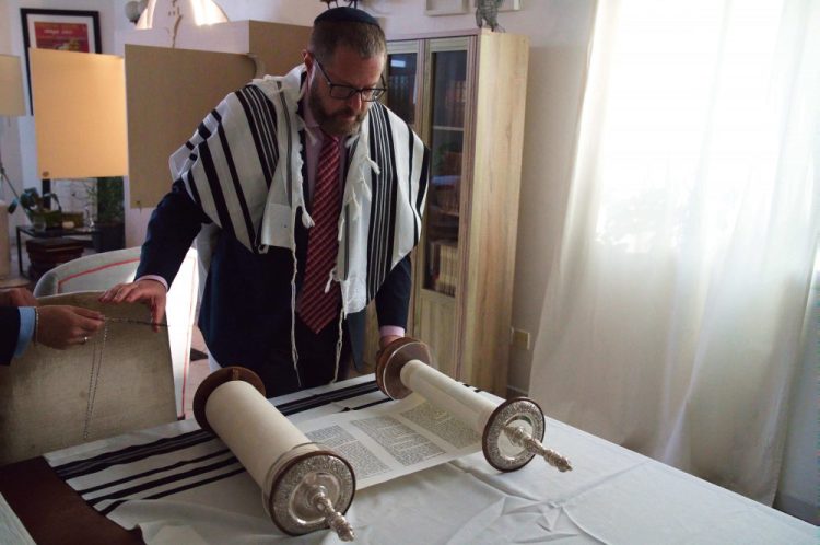 Alex Peterfreund, a co-founder of Dubai's Jewish community and its cantor, prepares to read from the Torah. Telephone service between the United Arab Emirates and Israel began working Sunday as the two countries opened diplomatic ties. 