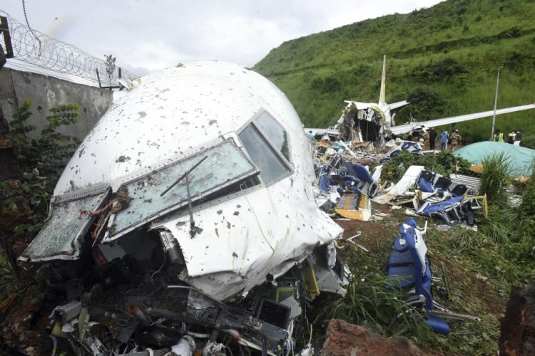 People stand by the debris of the Air India Express flight that skidded off a runway while landing in Kozhikode, Kerala state, India, on Saturday. The special evacuation flight was bringing people home who had been trapped abroad because of the coronavirus.

