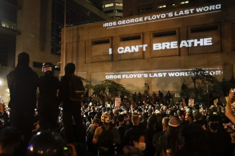The words "I can't breathe" are flashed on a wall during a Black Lives Matter protest in Portland, Ore., on July 25. S

