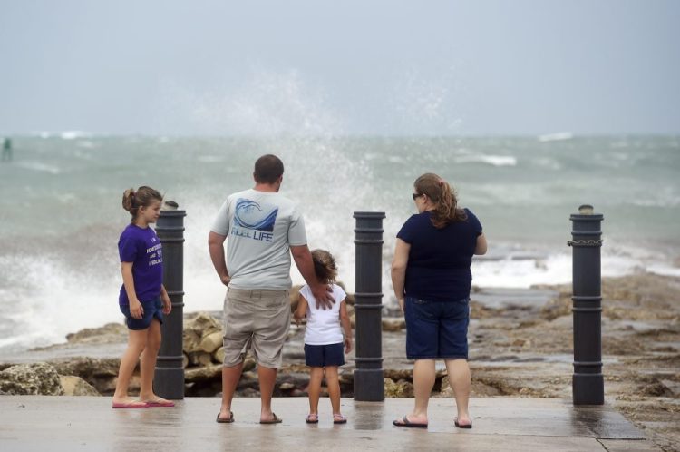 Elizabeth Whittemore (from left), along with her father James, sister Jordan and mother Susan, stand at the end of the South Jetty in Fort Pierce on Sunday, watching the waves crash over the rocks brought by the high winds of Tropical Storm Isaias churning off the coast.