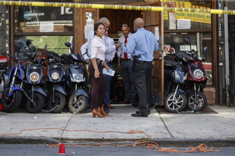 Police officers respond to a crime scene on Nostrand Avenue, where a 23-year-old man was discovered with gunshot wounds to his legs and torso before being transported to a hospital where he died from his injuries, in the Brooklyn borough of New York on July 18. 