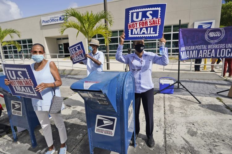 Protesters demonstrate during a National Day of Action to Save the Peoples Post Office! outside the Flagler Station post office in August in Miami. A federal judge found Thursday that President Trump and the U.S. Postal Service chief “are involved in a politically motivated attack on the efficiency of the Postal Service." 