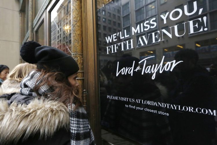 Women peer in the front door of Lord & Taylor's flagship Fifth Avenue store which closed for good in New York in 2019. 