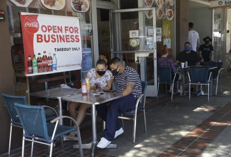 Josefina Pacheco, front left, and her husband Norberto wait to have a meal served outside at a restaurant in Burbank, Calif., in July. Restaurant chains are reporting they're paying more, but that doesn't mean they're filling their staff openings.