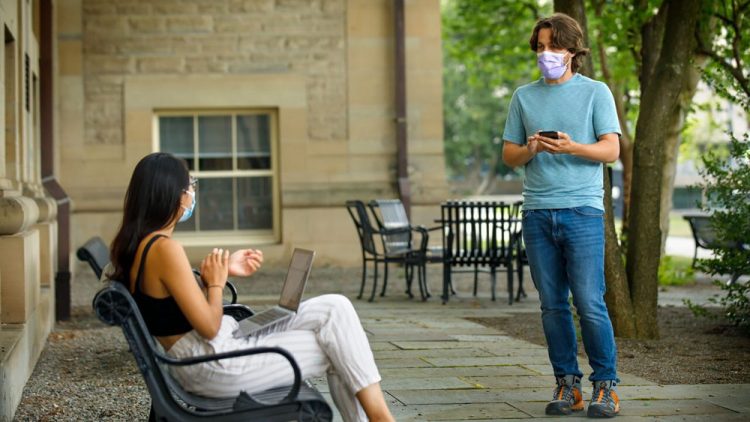 Bryan Maley, right, a grad student in the Master of Public Health program, interviews a student on campus about mask-wearing experiences as part of a public health survey, July 30 in Ithaca, N.Y.