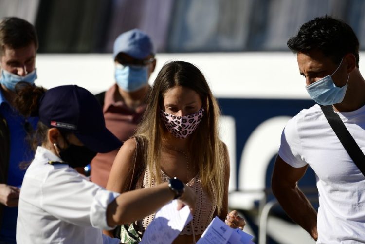A ship company worker checks passengers' health questionnaires prior to their boarding, at the port of Piraeus, near Athens, on Sunday
