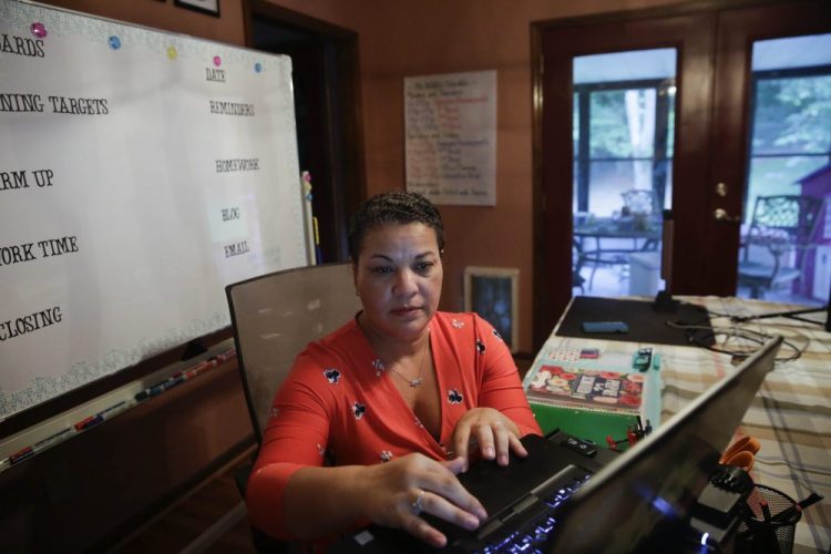 Aimee Rodriguez Webb works on her computer reading emails at her dinning room table that she set up as a virtual classroom.