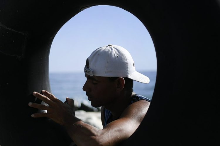 Larry Jimenez, 34, inflates his inner tube in preparation for open sea fishing, at Playa Escondida in La Guaira, Venezuela, on Friday. 

