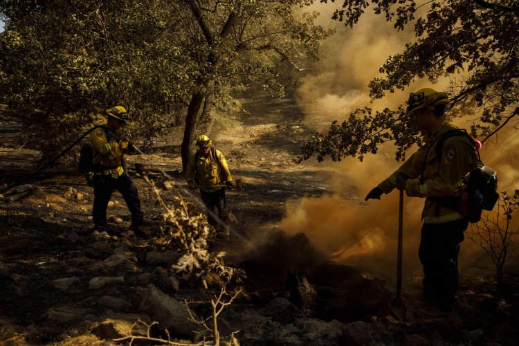 Firefighters extinguish a hot spot while working to contain the Apple fire in Yucaipa, Calif., on Aug. 4.
