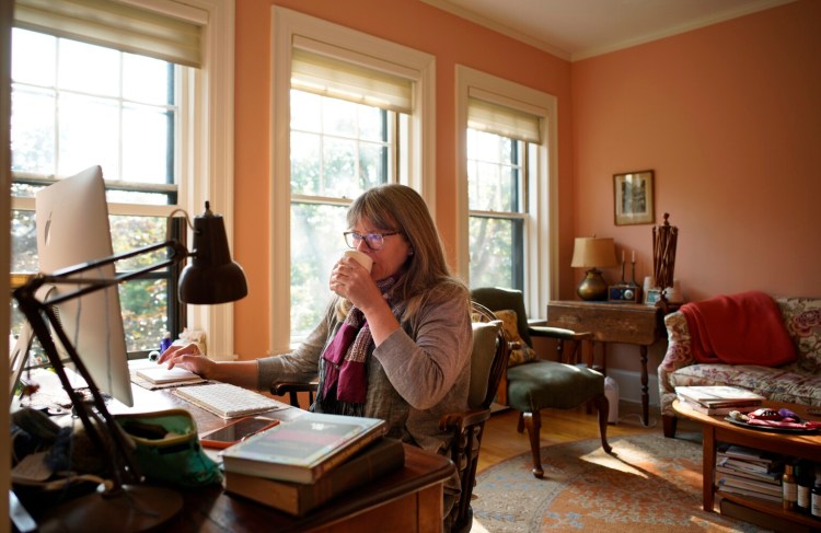 PORTLAND, ME - SEPTEMBER 10: Clara Parkes, an author who lives in Brooksville, sips tea while working on her computer in her Portland apartment on Thursday, September 10, 2020. Parkes keeps the apartment in Portland for when she needs to do work that demands a strong broadband connection, something she lacks in Brooksville. (Staff Photo by Gregory Rec/Staff Photographer)