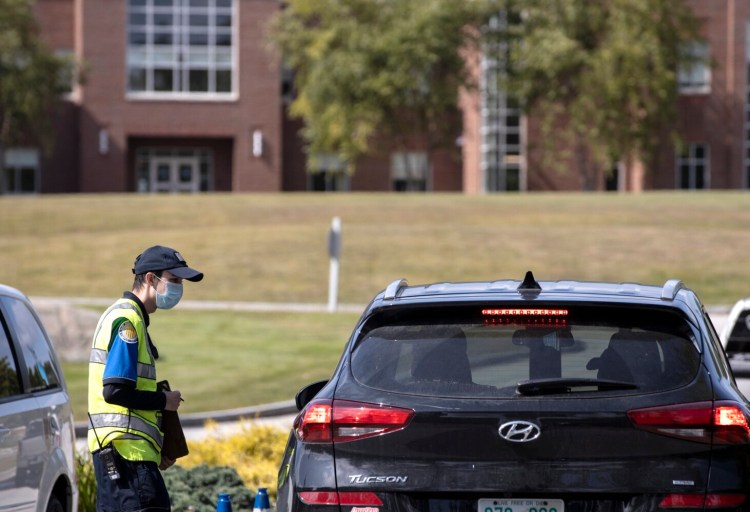 A campus security person talks to people coming into campus at the main entrance checkpoint at Saint Joseph's College in Standish on Sunday. The college reported nine positive cases of COVID-19 on campus and is implementing a  "study-in-place" program for the next two weeks. The campus security officer said that they will be out there 24/7. 