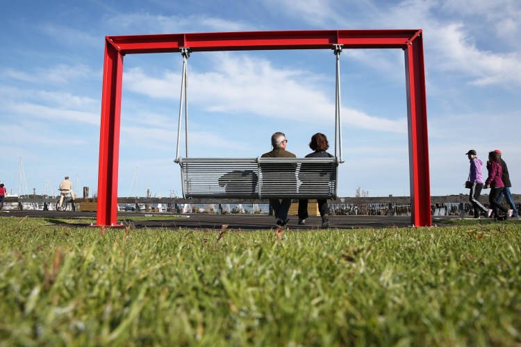Kirk and Sara Reichard of Chester County, Pa., sit in one of two swings at a new park that opened Friday on Amethyst Lot in Portland. The waterfront park is next to Eastern Prom Trail and Ocean Gateway.  Ben McCanna/Staff Photographer