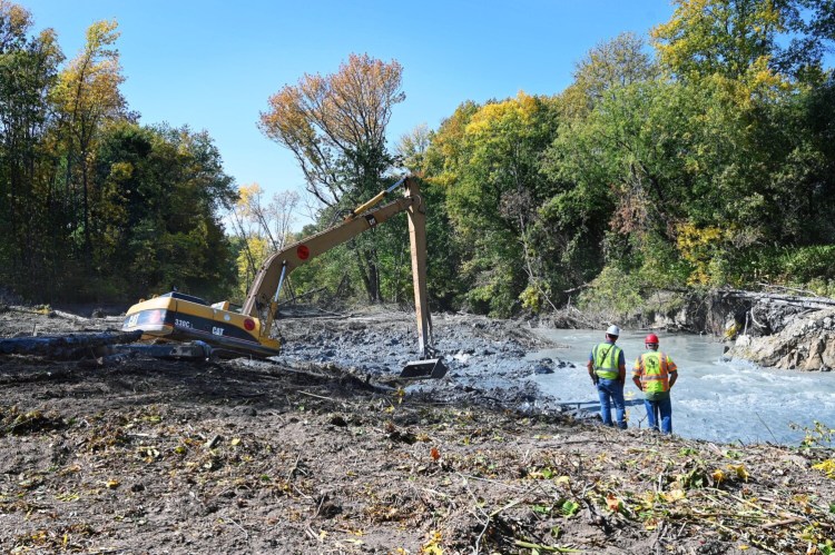 A crew with Shaw Brothers use an excavator to move debris to open up the channel of the Presumpscot River in Westbrook Tuesday. A large landslide completely blocked the Presumpscot River in Westbrook earlier this month.