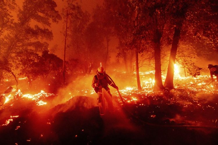 A firefighter battles the Creek Fire as it threatens homes in the Cascadel Woods neighborhood of Madera County, Calif., on Monday. 