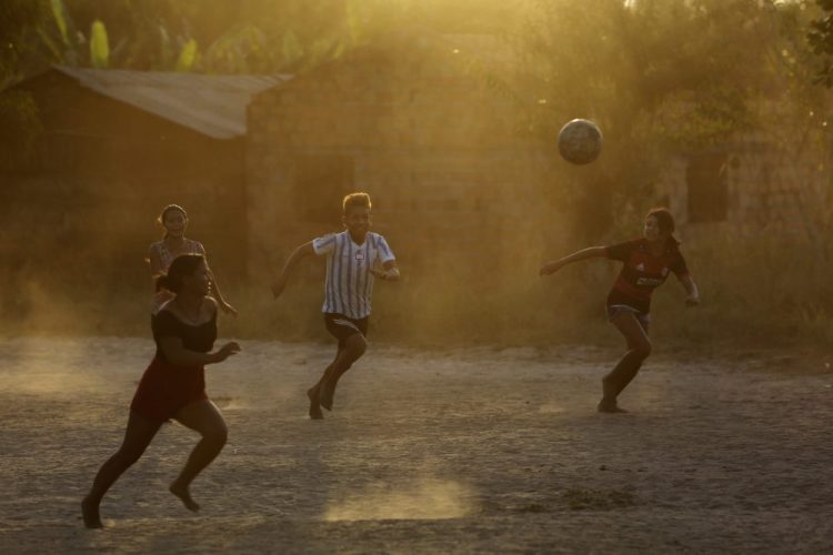 Tenetehara Indigenous youth play ball at dusk in the Alto Rio Guama Indigenous Reserve, near the city of Paragominas, Brazil, Monday. The Indigenous group, also known as Tembe, held a festival this week to celebrate and give thanks that none of their members have fallen ill with COVID-19, after closing their area off in March. (AP Photo/Eraldo Peres)