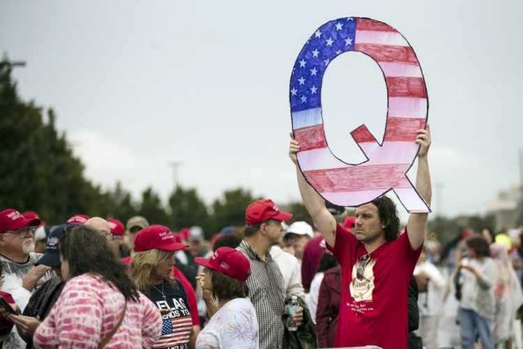 A protester holding a Q sign waits in line with others to enter a campaign rally with President Donald Trump in Wilkes-Barre, Pa. in August. 