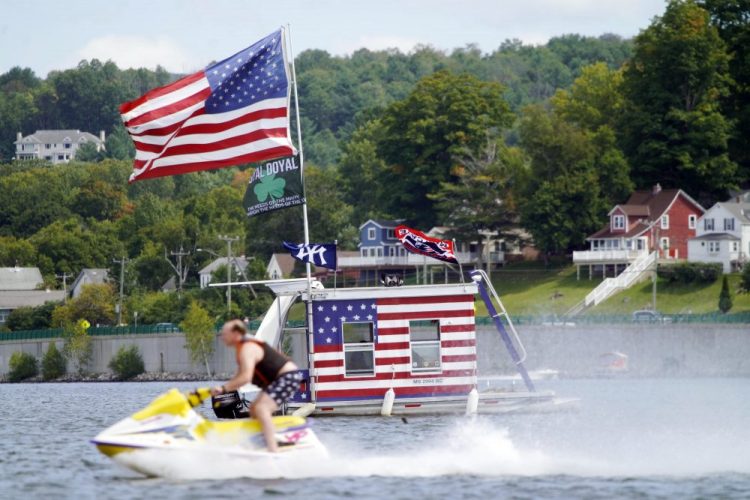 A jet skier passes a patriotic shanty-boat owned by AJ Crea on Pontoosuc Lake on Labor Day in Pittsfield, Mass.