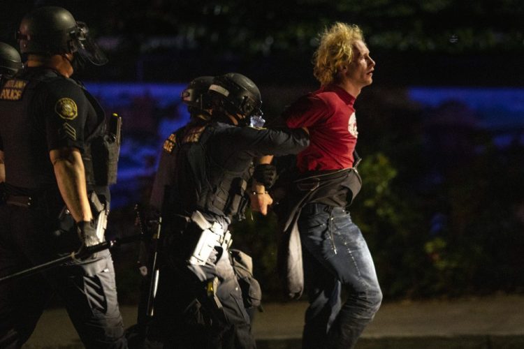 Portland police make arrests during the nightly protests at a Portland police precinct on Sunday in Portland, Ore. Oregon State Police will return to Portland to help local authorities after the fatal shooting of a man following clashes between President Trump supporters and counter-protesters that led to an argument between the president and the city's mayor over who was to blame for the violence. 