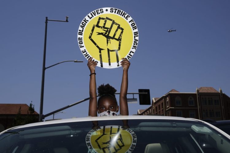 Audrey Reed, 8, holds up a sign through the sunroof of a car during a July 20 rally in Los Angeles. 