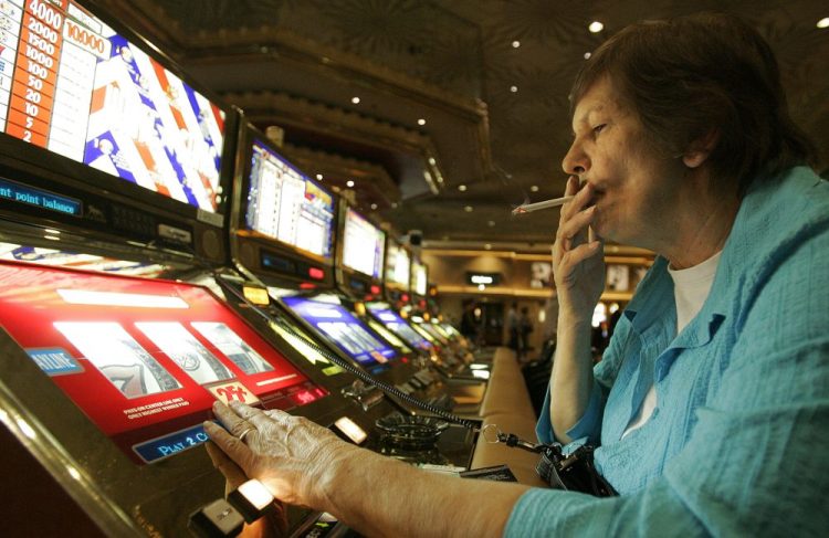 Judy King of Daytona Beach, Fla., holds her cigarette while playing a slot machine at the MGM Grand in Las Vegas in 2005. One of the last Vegas Strip resorts to reopen after coronavirus closures will be the first to be smoke-free, MGM Resorts International announced Monday. 