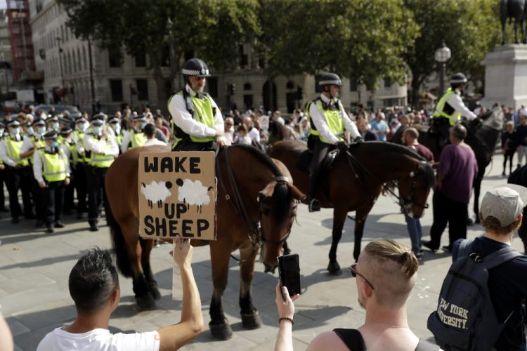 A protester holds up a placard in front of police officers during a "Resist and Act for Freedom" protest against a mandatory coronavirus vaccine, wearing masks, social distancing and a second lockdown, in Trafalgar Square in London on Saturday.  