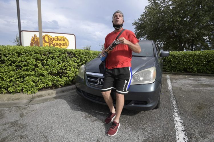 Jeff Lello stands in front of the van in which he lives, in the parking lot of a Cracker Barrel restaurant. He became homeless after being laid off from his job as a waiter at an Orlando, Fla., restaurant because of the pandemic. (AP Photo/Phelan M. Ebenhack)