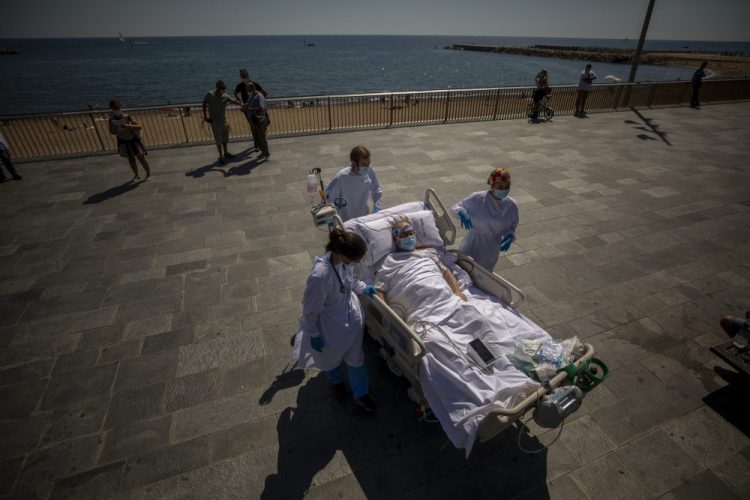 Francisco España, 60, is transported back to the hospital after spending a few minutes by the promenade, in Barcelona, Spain, on Friday. Researchers have anecdotally noticed that even 10 minutes in front of the blue sea waters can improve a patient’s emotional attitude.  (AP Photo/Emilio Morenatti)