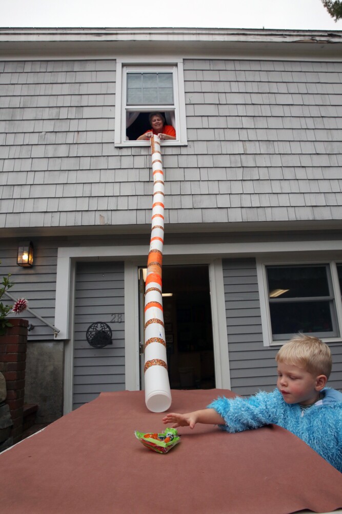  Julie Otte of Cumberland and her grandson Logan Otte, 2, demonstrate a 10-foot-long candy chute made with Clorox wipes containers and candy corn duct tape. 