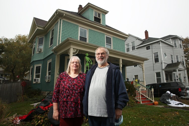 Charlie and Cheryl Wallace, standing in front of their house in Portland on Wednesday, will be at home a lot this winter and will benefit from low heating oil prices, as will thousands of other Mainers.