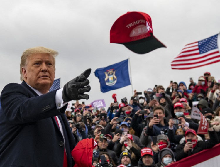 President Trump tosses a cap during a campaign stop in Waterford Township, Mich., on Friday. 