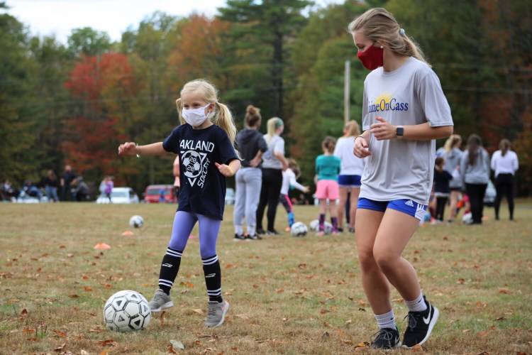 First grader Raegan Marston shares her dribbling skills with Lady Eagles soccer player Katie True at ShineOn Saturday, an annual event to link local girls with the Messalonskee girls soccer players for a day of mentorship in honor of Cassidy Charette. 