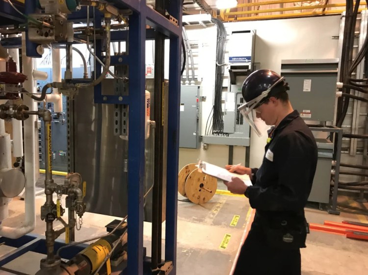 A technician takes a reading from an apparatus that turns wood waste into biofuel in this 2017 photo of Biofine's test facility in Old Town. The company plans to open another facility in Maine to produce its zero-emission heating oil on a commercial scale.