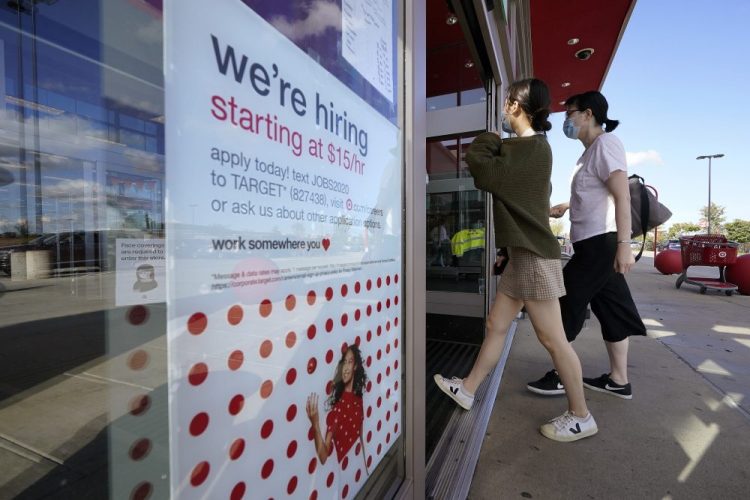Passers-by walk past a hiring sign as they enter a Target retail store location, Wednesday in Westwood, Mass. The number of Americans seeking unemployment benefits declined last week to a still-high 837,000, evidence that the economy is struggling to sustain a tentative recovery that began this summer.