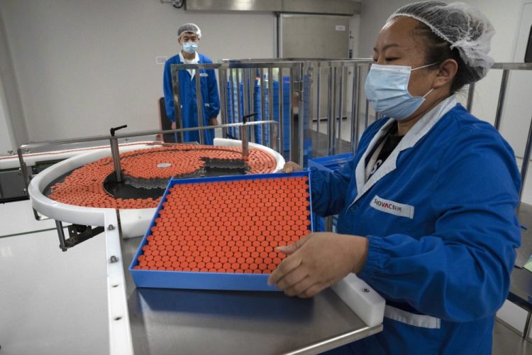 A worker feeds vials for production of SARS CoV-2 Vaccine for COVID-19 at the SinoVac vaccine factory in Beijing last month. China said on Friday that it is joining the COVID-19 vaccine alliance known as COVAX.