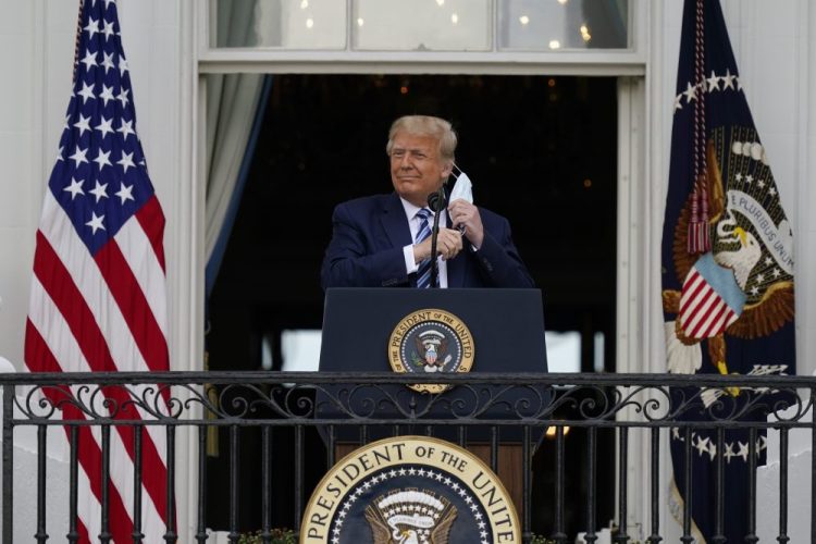 President Trump removes his face mask to speak from the Blue Room Balcony of the White House to a crowd of supporters on Saturday in Washington.