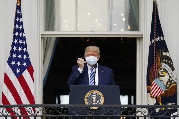 President Trump removes his mask to speak from the Blue Room Balcony of the White House on Saturday. The president was cleared Sunday to return to the campaign trail, but the announcement comes after his doctor said he was no longer at risk of transmitting the coronavirus but did not say explicitly whether Trump had tested negative for it.
