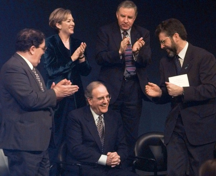 Former U.S. Senator and Chairman of the Northern Ireland Peace Talks, George Mitchell, center, smiles as he is applauded by fellow recipients of the John F. Kennedy Profile in Courage Award, John Hume, left, of the Social Democratic and Labour Party and Gerry Adams, right, of Sein Fein during a ceremony in Boston, in 1998.  In all, eight political leaders of Northern Ireland and Mitchell received the award in recognition of their negotiation of the Good Friday Peace Agreement. 

