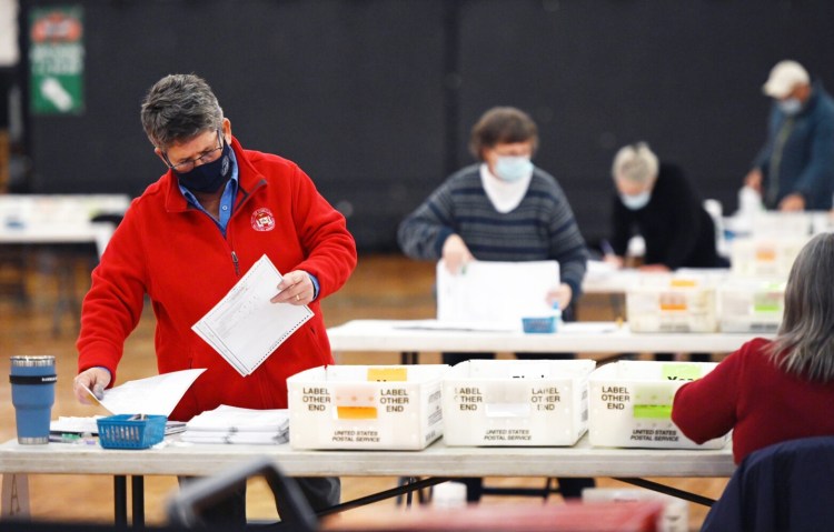 Kathy Alves, left, and others go through ballots during the recount process of referendum question E at the Portland Expo on Thursday.
